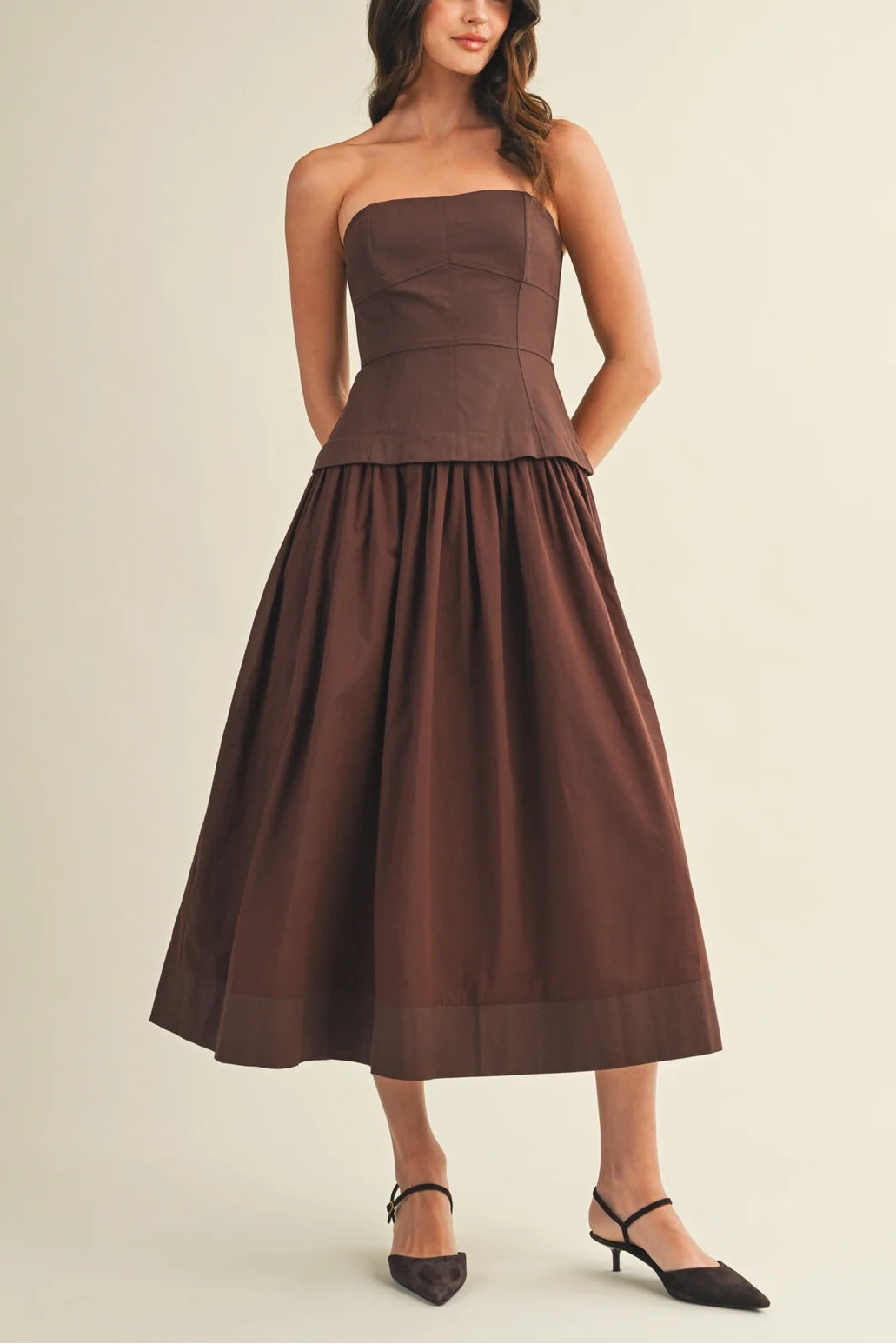 Woman wearing a brown strapless dress on a beige background